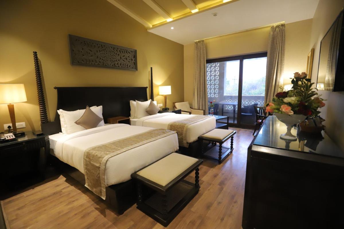 a large hotel room with two beds and a window at Essentia Luxury Resort & Spa Udaipur in Udaipur