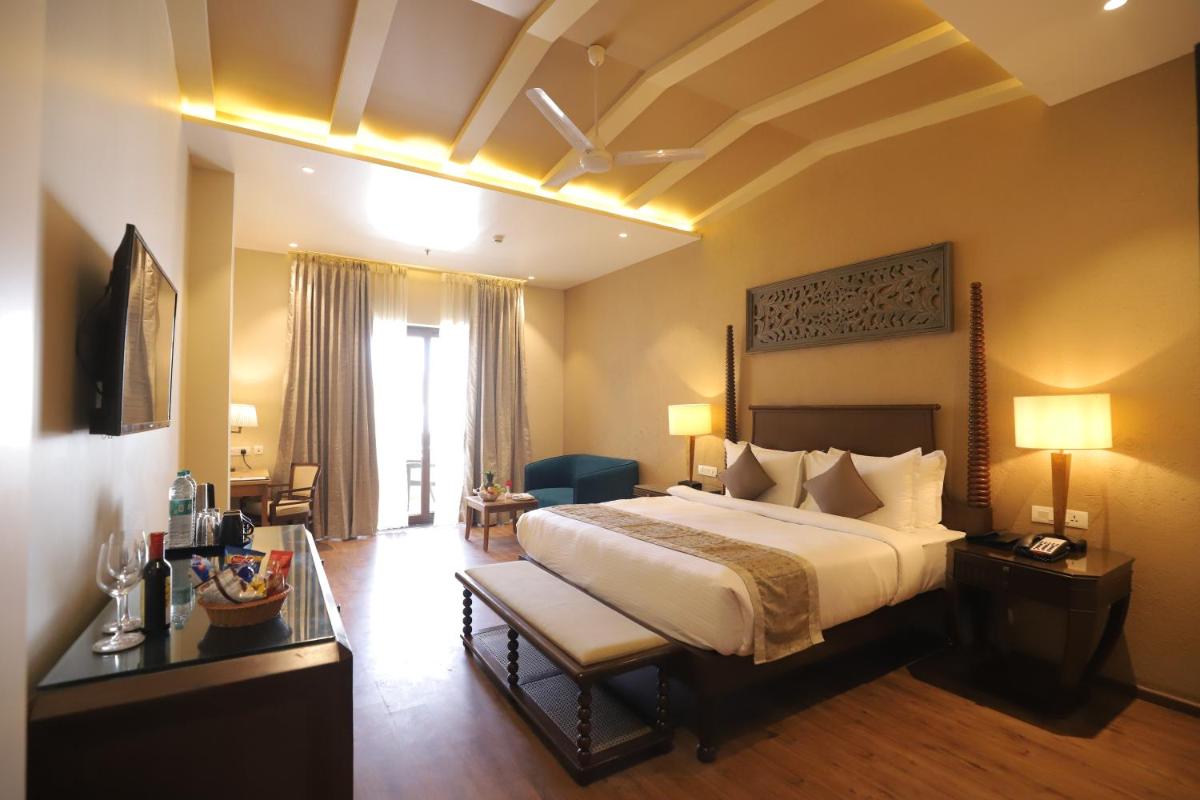 a hotel room with a large bed and a table at Essentia Luxury Resort & Spa Udaipur in Udaipur