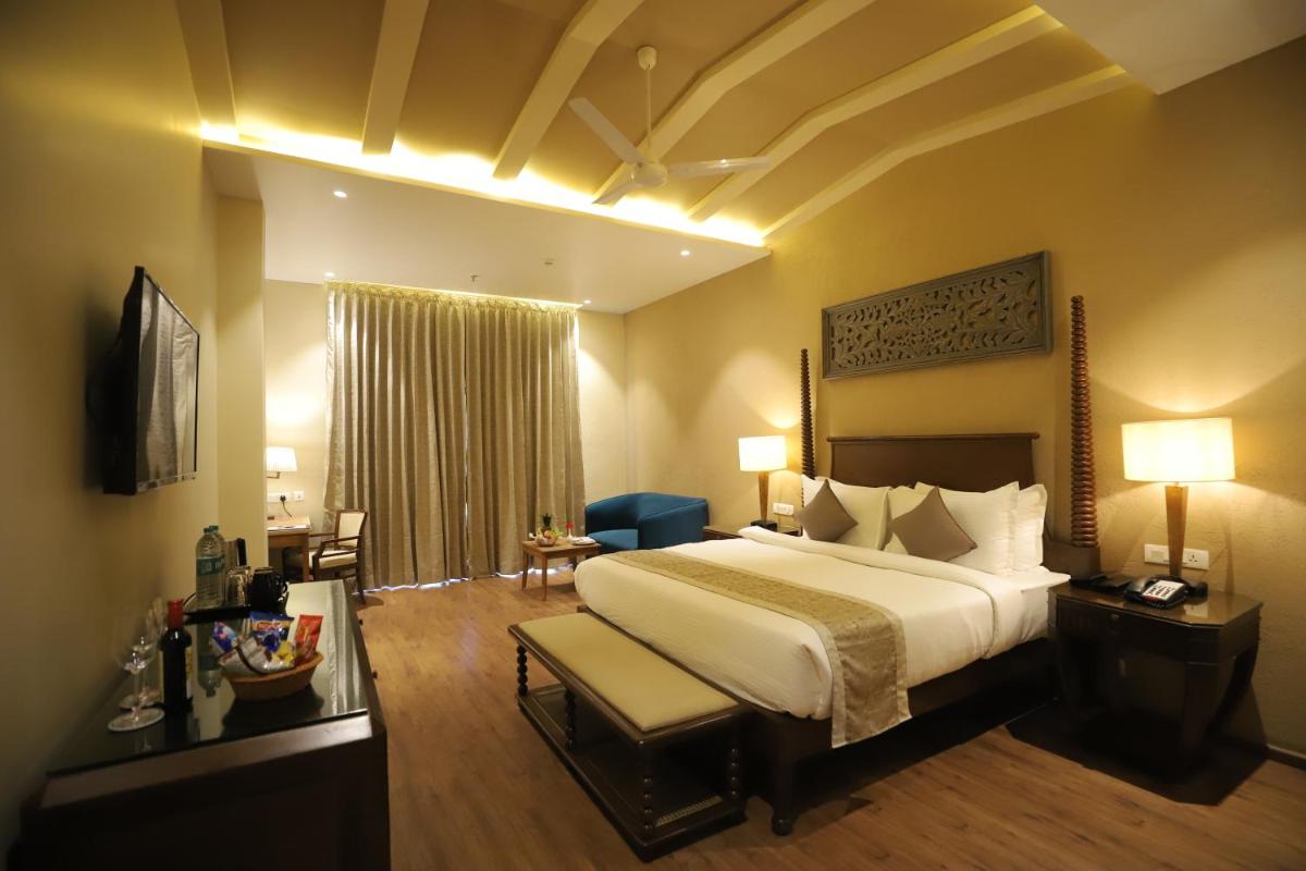 a hotel room with a large bed and a chair at Essentia Luxury Resort & Spa Udaipur in Udaipur
