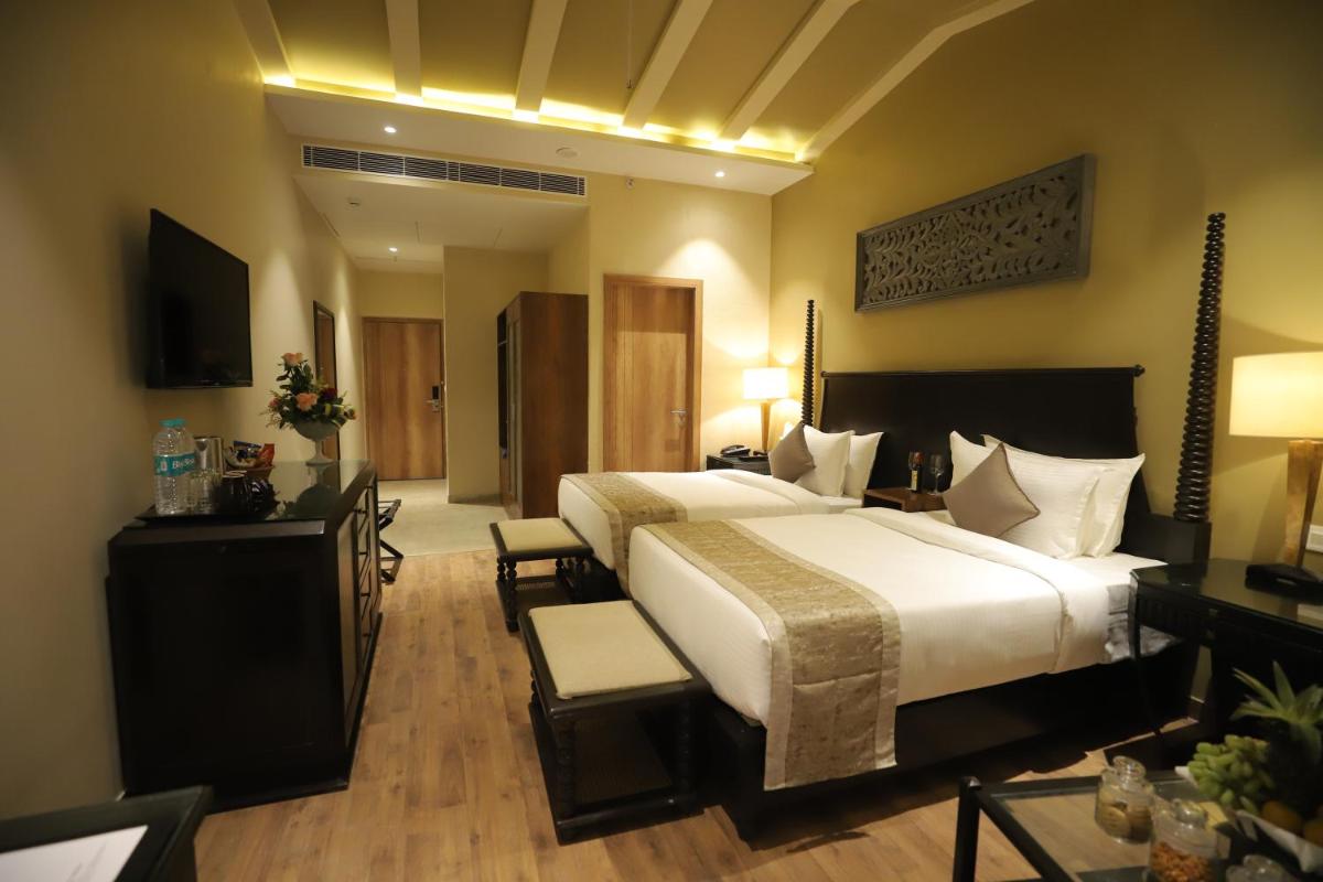 a hotel room with a large bed and a television at Essentia Luxury Resort & Spa Udaipur in Udaipur