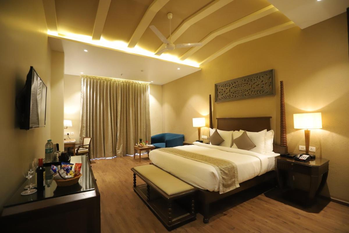 a hotel room with a large bed and a desk at Essentia Luxury Resort & Spa Udaipur in Udaipur