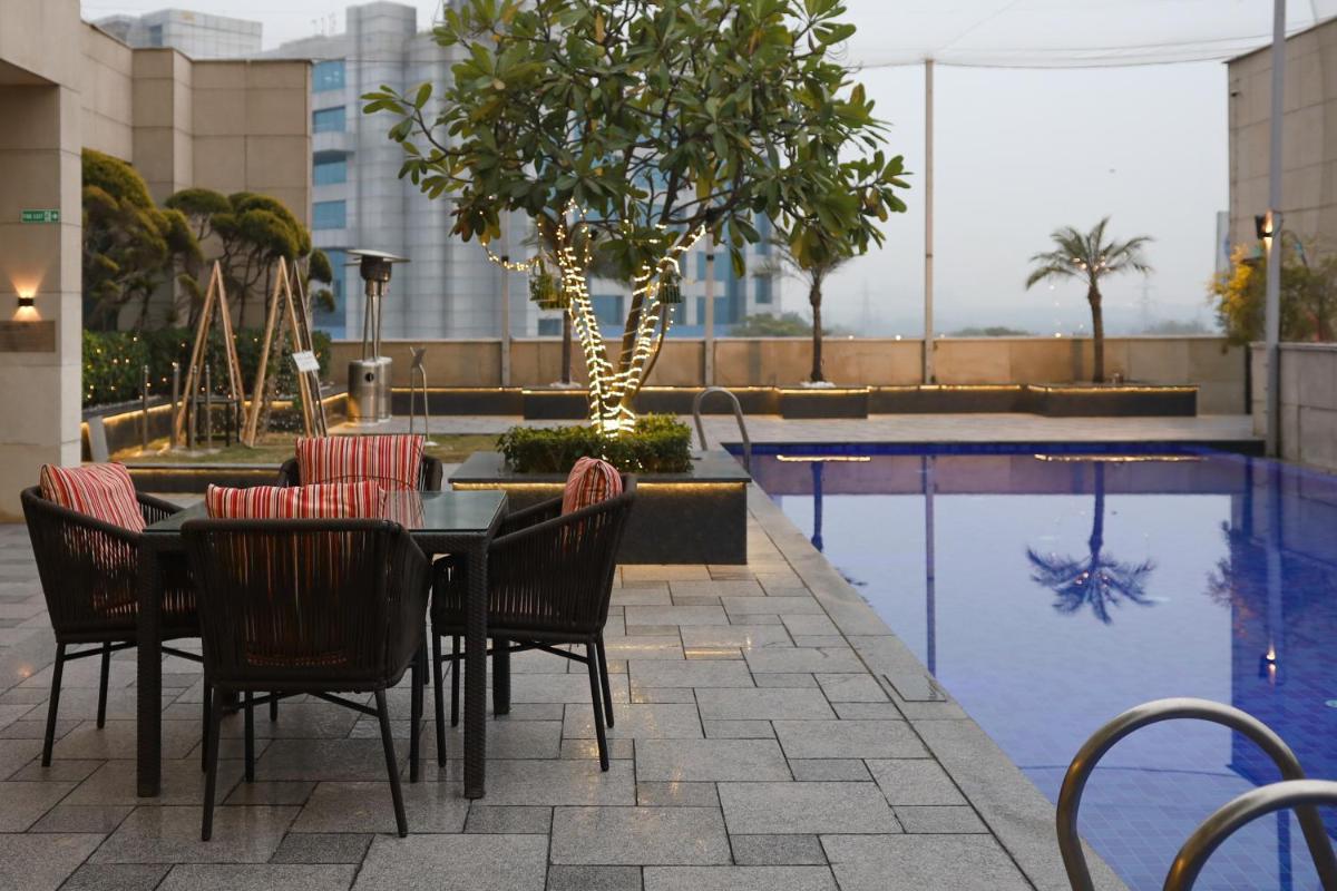 a patio with a table and chairs next to a pool at Crowne Plaza New Delhi Okhla by IHG in New Delhi