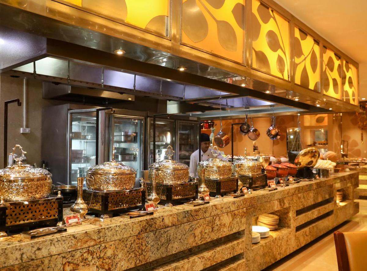a chef preparing food in a restaurant kitchen at Crowne Plaza New Delhi Okhla by IHG in New Delhi
