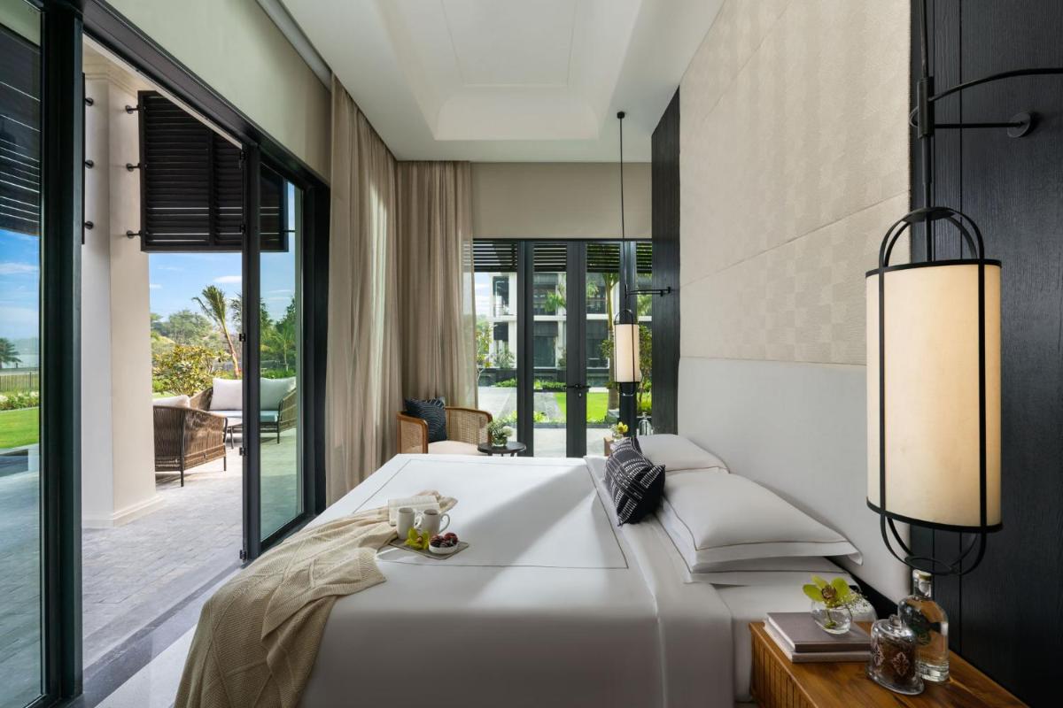 a bedroom with a large white bed and large windows at Taj Taal Kutir in Kolkata a bedroom with a large white bed and large windows at Taj Taal Kutir in Kolkata