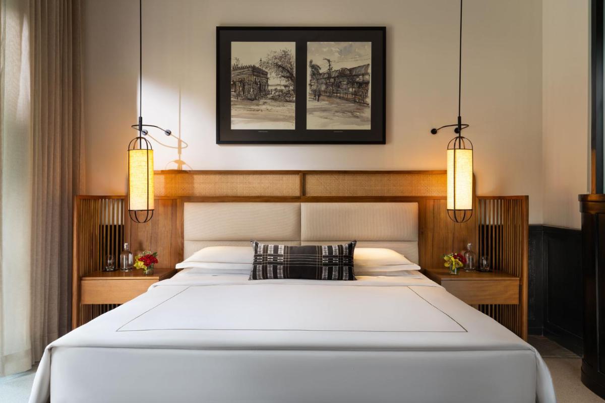 a bedroom with a large white bed with two lights at Taj Taal Kutir in Kolkata