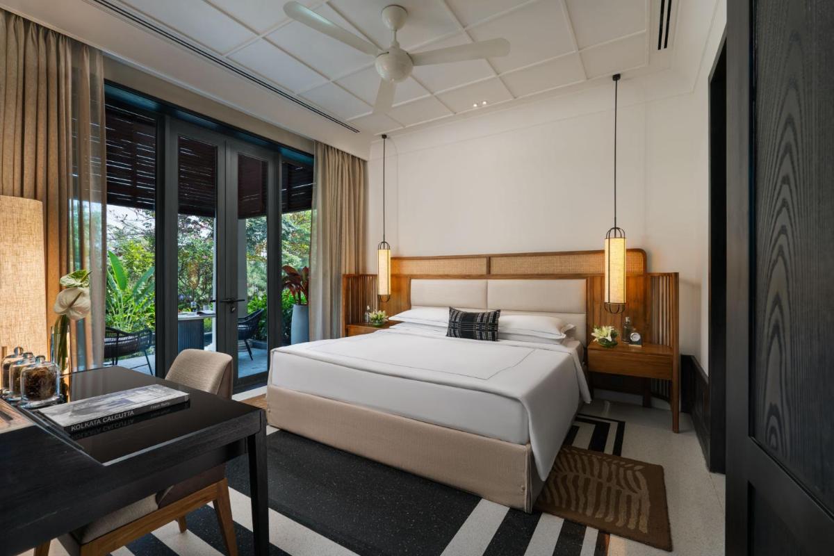 a bedroom with a white bed and a desk and a desk at Taj Taal Kutir in Kolkata