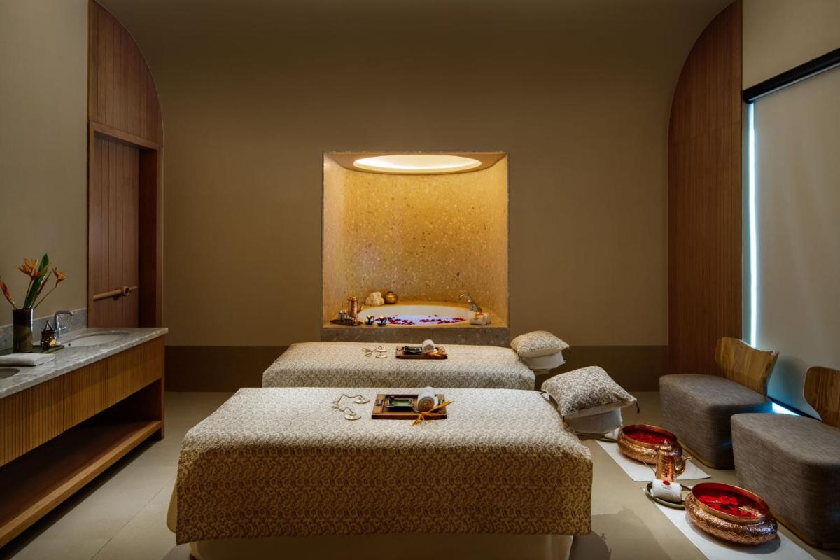 two beds in a hotel room with a bed and a mirror at Taj Taal Kutir in Kolkata