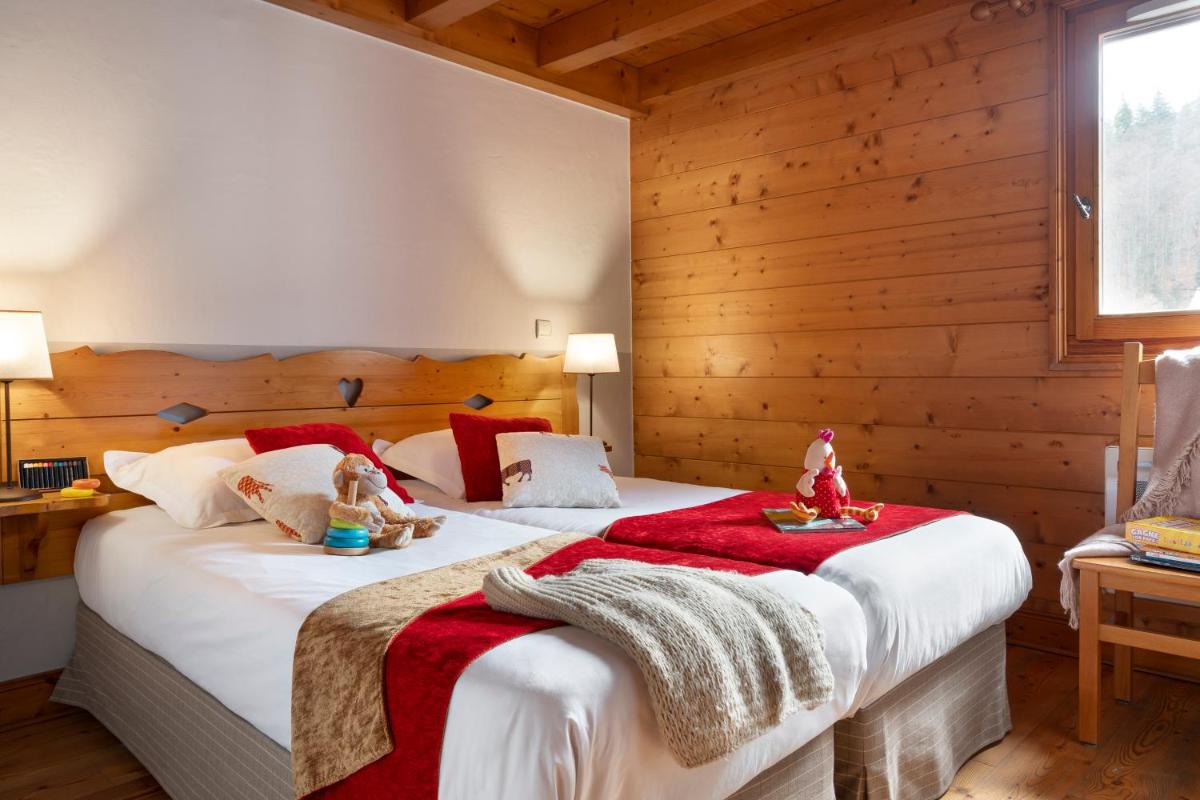 - une chambre avec 2 poupées assises sur un lit dans l'établissement Résidence Pierre & Vacances Premium Les Fermes Du Soleil, aux Carroz d'Arâches