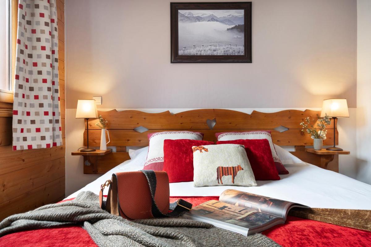 une chambre avec un lit avec des oreillers rouges dans l'établissement Résidence Pierre & Vacances Premium Les Fermes Du Soleil, aux Carroz d'Arâches