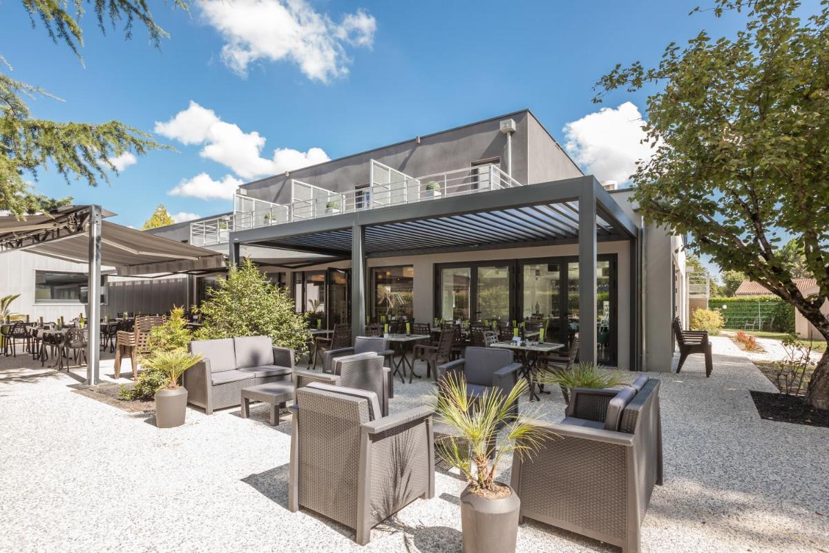 - un bâtiment doté d'une terrasse avec des chaises et des tables dans l'établissement Logis Hotel Restaurant & SPA Au Comte d'Ornon, à Gradignan