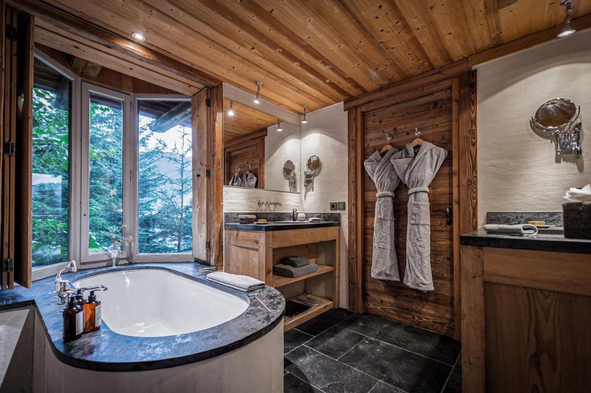 - une salle de bains avec une grande baignoire dans une maison en bois dans l'établissement Zannier Le Chalet, à Megève