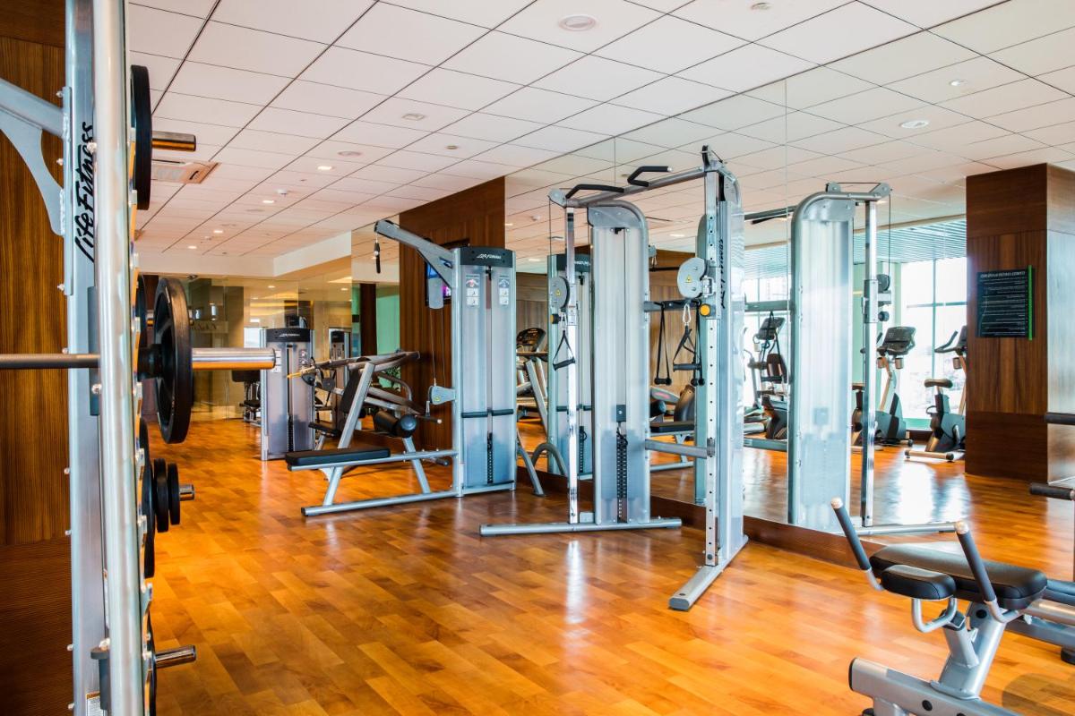a gym with several tread machines in a room at Oakwood Residence Kapil Hyderabad in Hyderabad