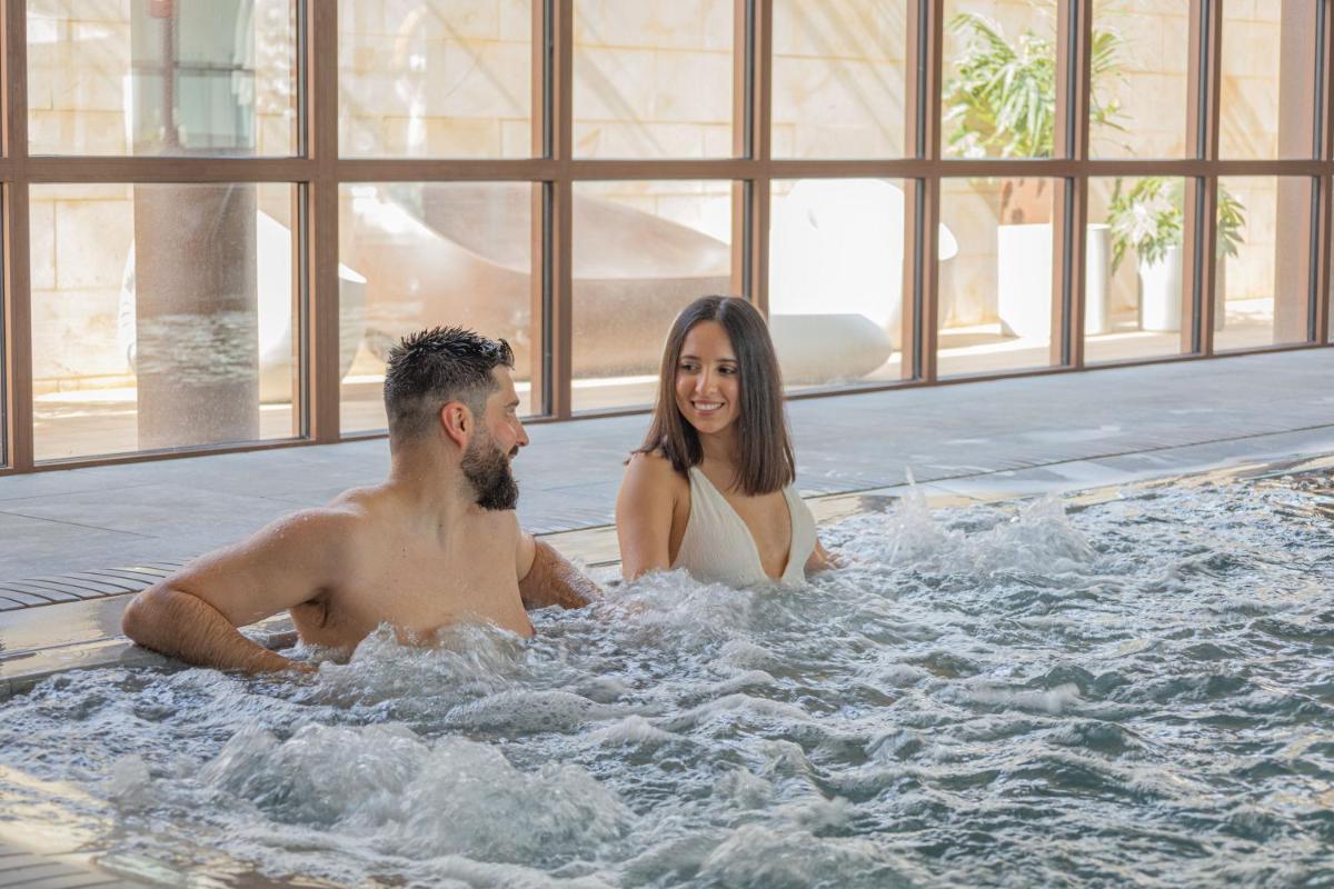 Un hombre y una mujer sentados en un jacuzzi en Seth Port Ciutadella, en Ciutadella
