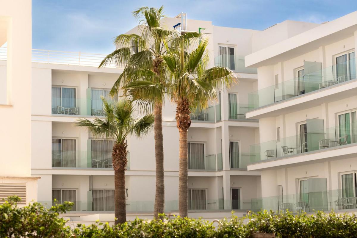 dos palmeras frente a un edificio en Hotel Capricho, en Cala Ratjada