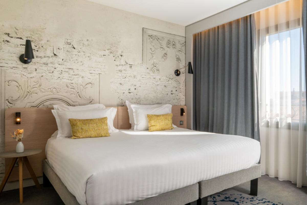 - une chambre avec un grand lit blanc et des oreillers jaunes dans l'établissement Nemea Appart Hotel Cannes Palais, à Cannes