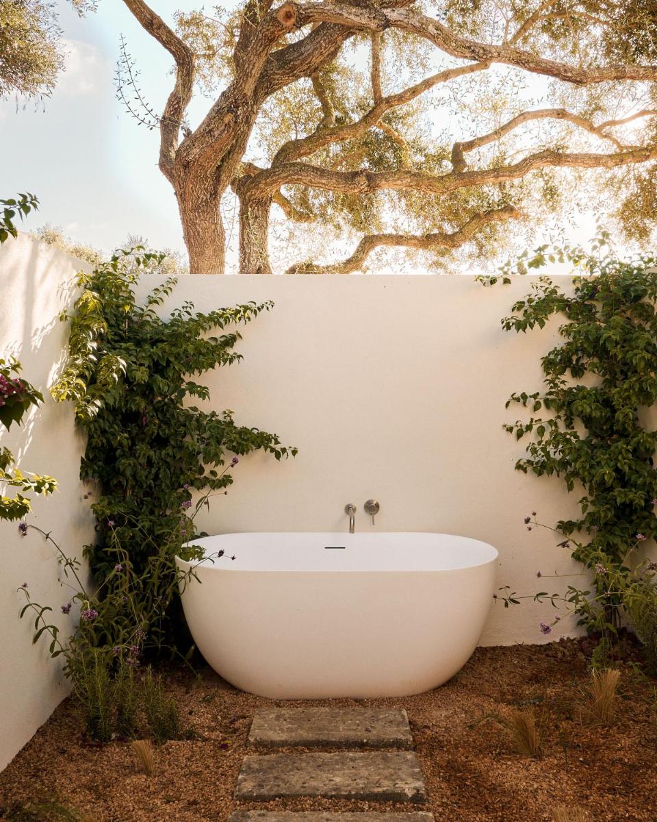 una bañera en un patio con un árbol en Morvedra Nou Luxury Boutique Hotel - Adults Only, en Ciutadella