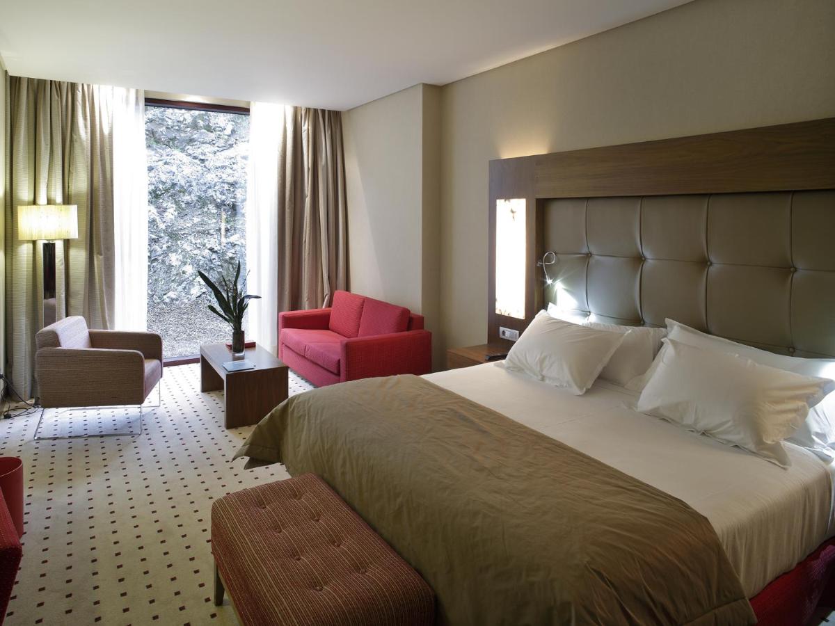 Una habitación de hotel con una cama grande y una silla roja. en Blau Gran Hotel Las Caldas - Adults Only, en Las Caldas