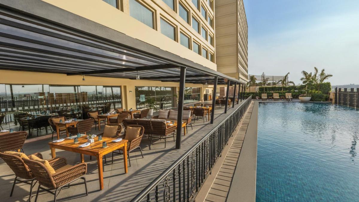 a hotel patio with tables and chairs next to a pool at Holiday Inn New Delhi Mayur Vihar Noida by IHG in New Delhi a hotel patio with tables and chairs next to a pool at Holiday Inn New Delhi Mayur Vihar Noida by IHG in New Delhi