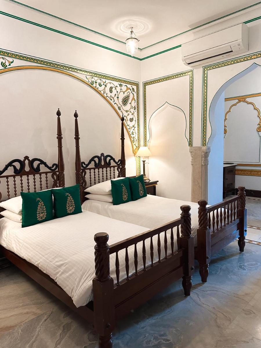 a bedroom with a large bed with green pillows at The Raj Palace (Small Luxury Hotels of the World) in Jaipur