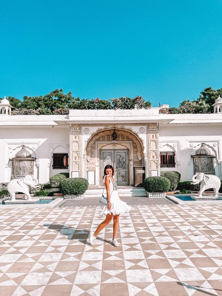 a woman in a white dress walking in front of a building at The Raj Palace (Small Luxury Hotels of the World) in Jaipur