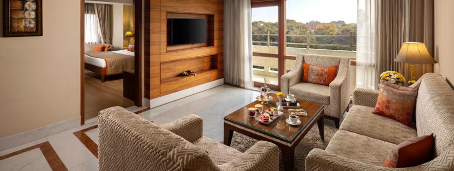 a living room with a couch and chairs and a living room with a television at Jaypee Vasant Continental in New Delhi