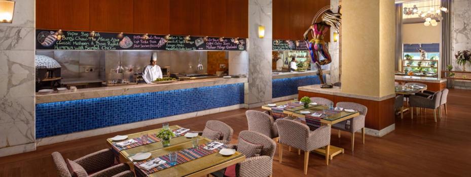 a restaurant with tables and chairs and a bar at Jaypee Vasant Continental in New Delhi