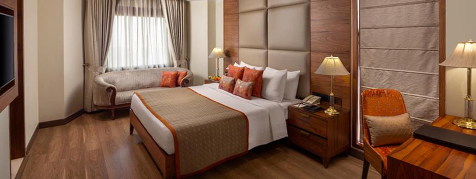 a hotel room with a large bed and a chair at Jaypee Vasant Continental in New Delhi