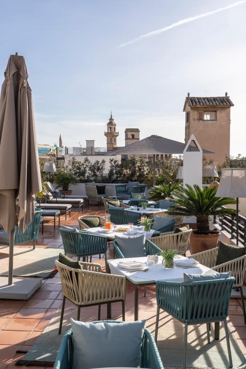 Un patio con mesas y sillas y una sombrilla. en Palacio Ca Sa Galesa, en Palma de Mallorca
