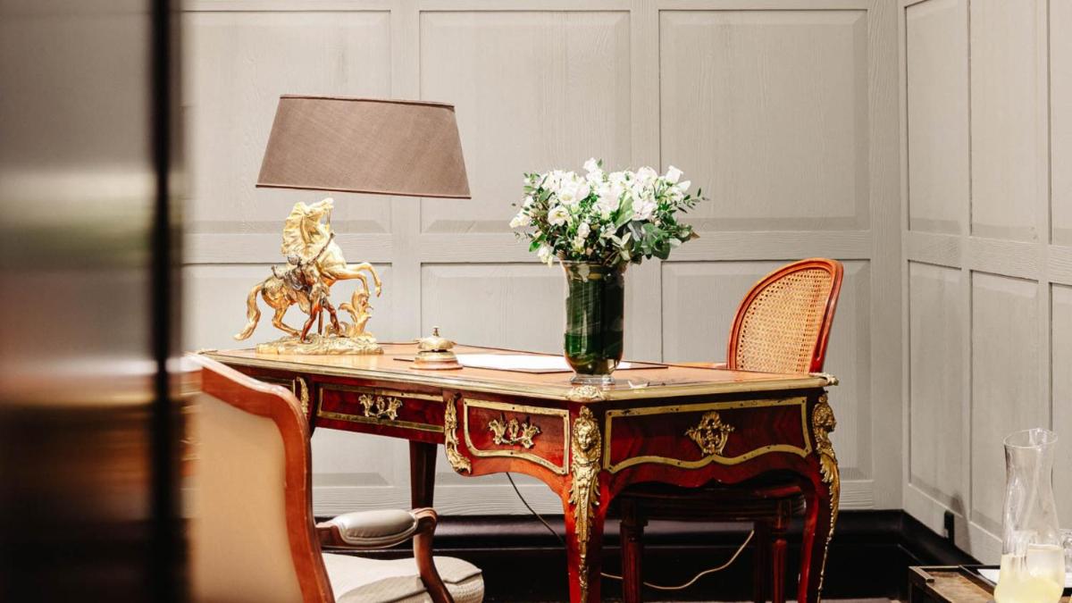 une table avec un vase de fleurs et une lampe dans l'établissement Hôtel Lancaster Paris Champs-Elysées, à Paris
