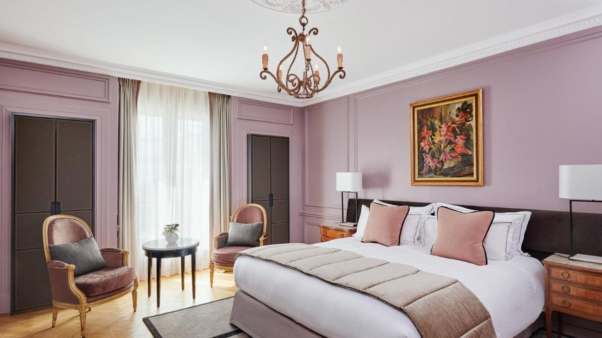 une chambre avec un grand lit et un lustre dans l'établissement Hôtel Lancaster Paris Champs-Elysées, à Paris