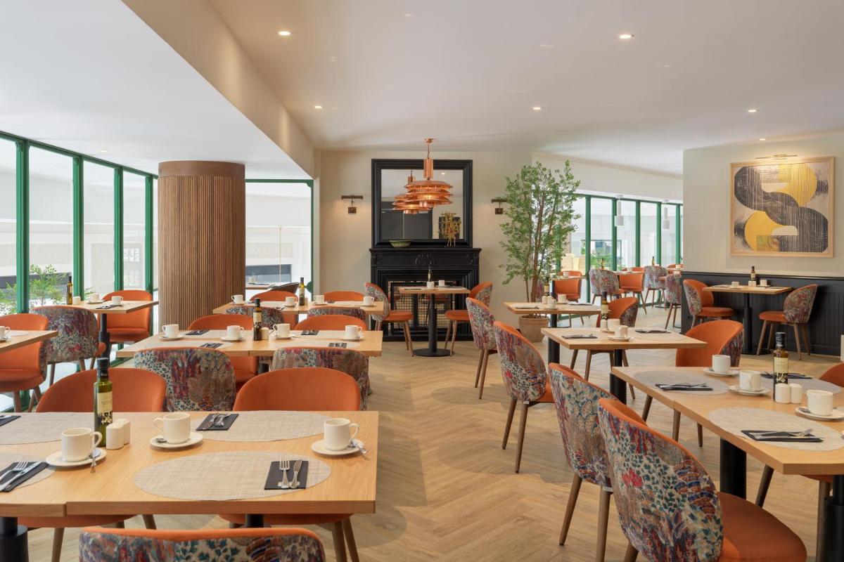 un restaurante con mesas, sillas y un piano en H10 Casanova, en Barcelona