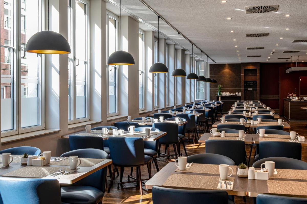 eine Reihe von Tischen und Stühlen in einem Restaurant in der Unterkunft Hilton Cologne in Köln eine Reihe von Tischen und Stühlen in einem Restaurant in der Unterkunft Hilton Cologne in Köln