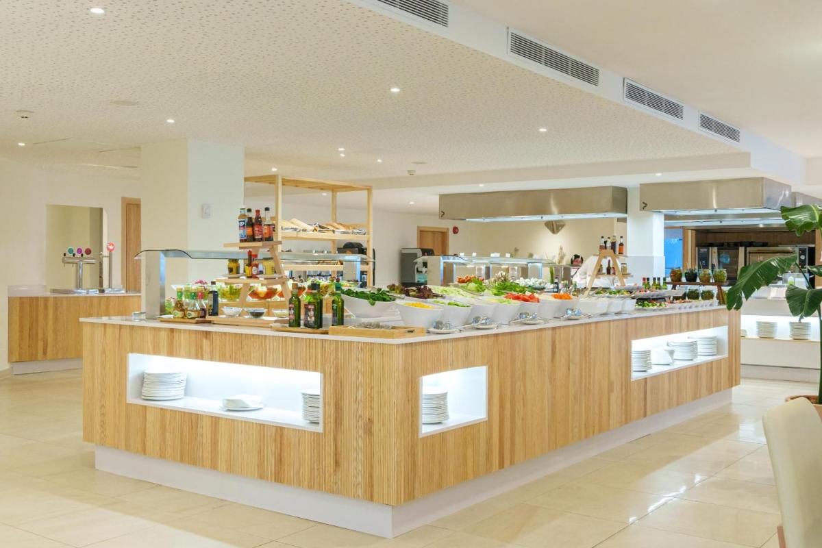 Un restaurante con un mostrador con comida. en Ferrer Janeiro Hotel & Spa, en Can Picafort