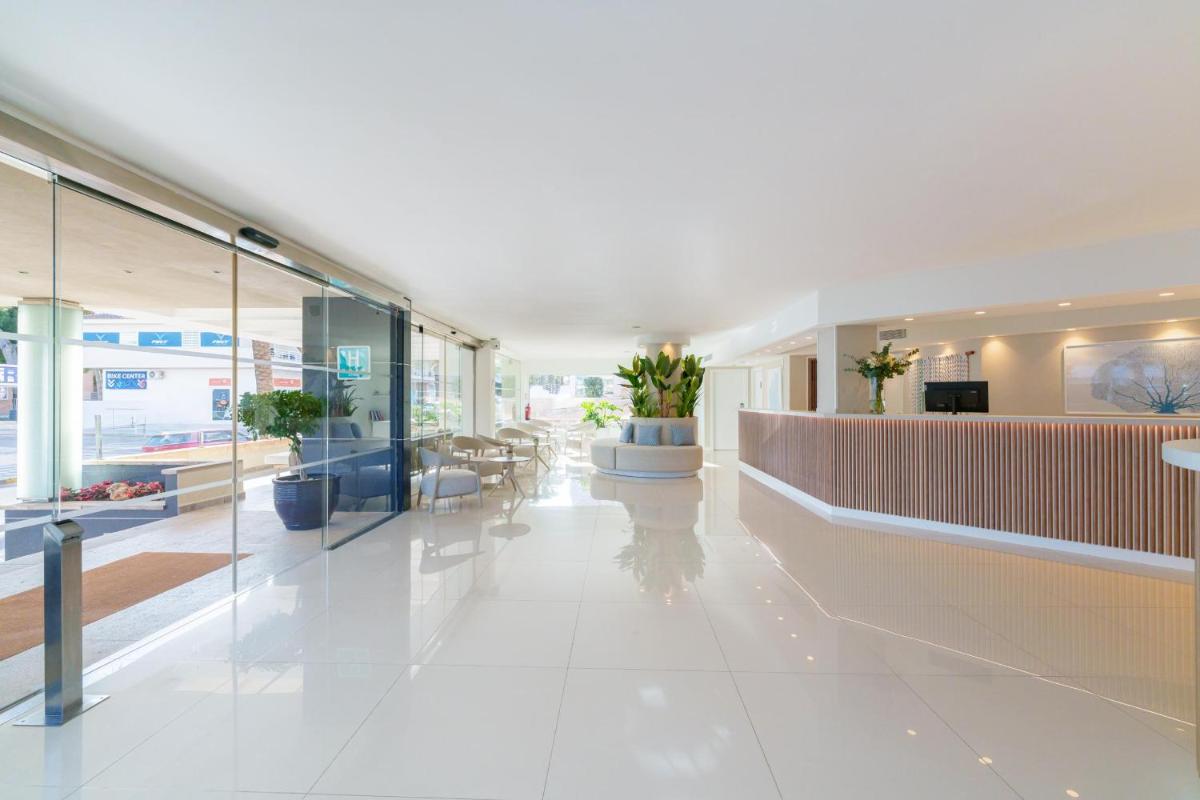 un vestíbulo de oficina con suelo blanco y paredes de cristal en Ferrer Janeiro Hotel & Spa, en Can Picafort