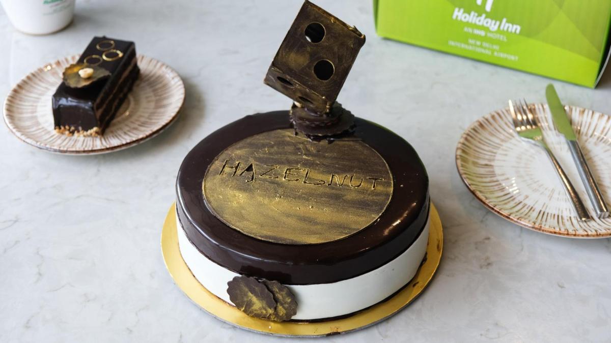 a chocolate cake on a table with plates and forks at Holiday Inn New Delhi Aerocity by IHG in New Delhi