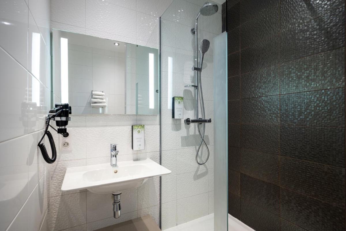 une salle de bain blanche avec un lavabo et une douche dans l'établissement Kyriad Prestige Saint-Malo, à Saint-Malo