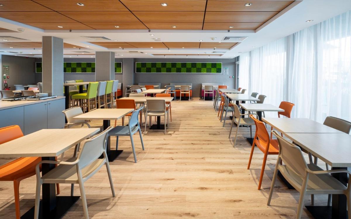 une salle à manger avec des tables et des chaises dans une cafétéria dans l'établissement Kyriad Prestige Saint-Malo, à Saint-Malo