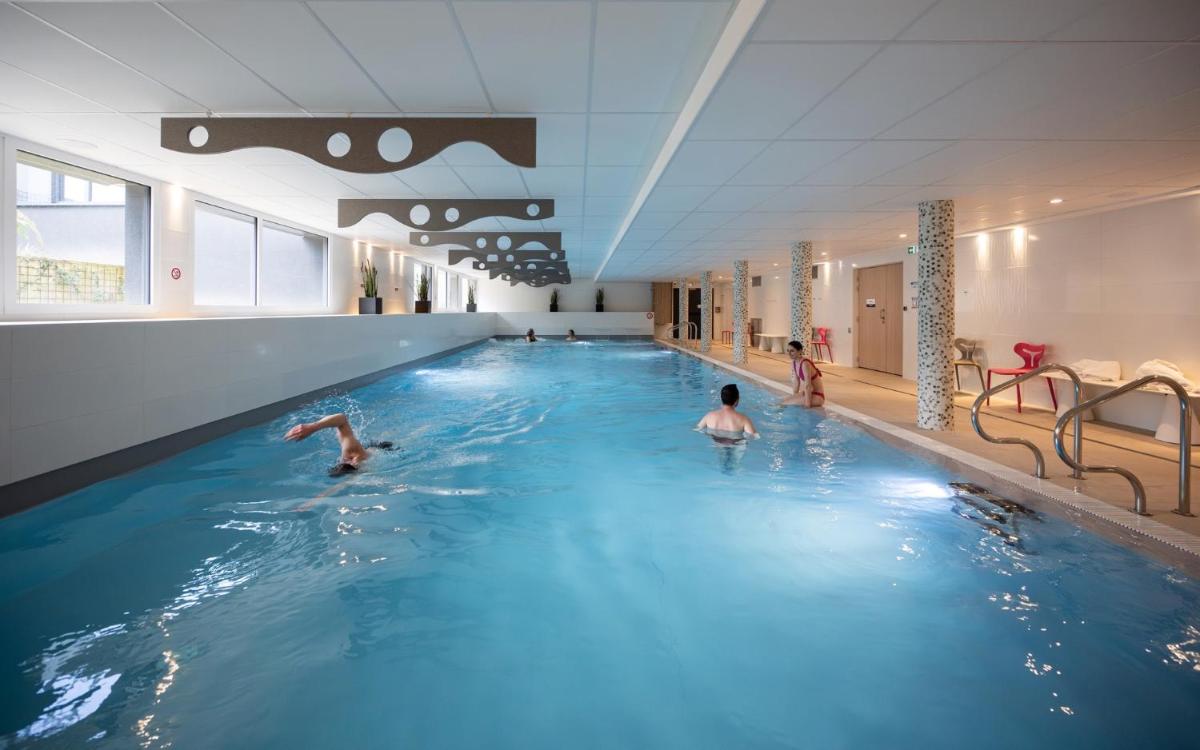 un groupe de personnes nageant dans une piscine dans l'établissement Kyriad Prestige Saint-Malo, à Saint-Malo