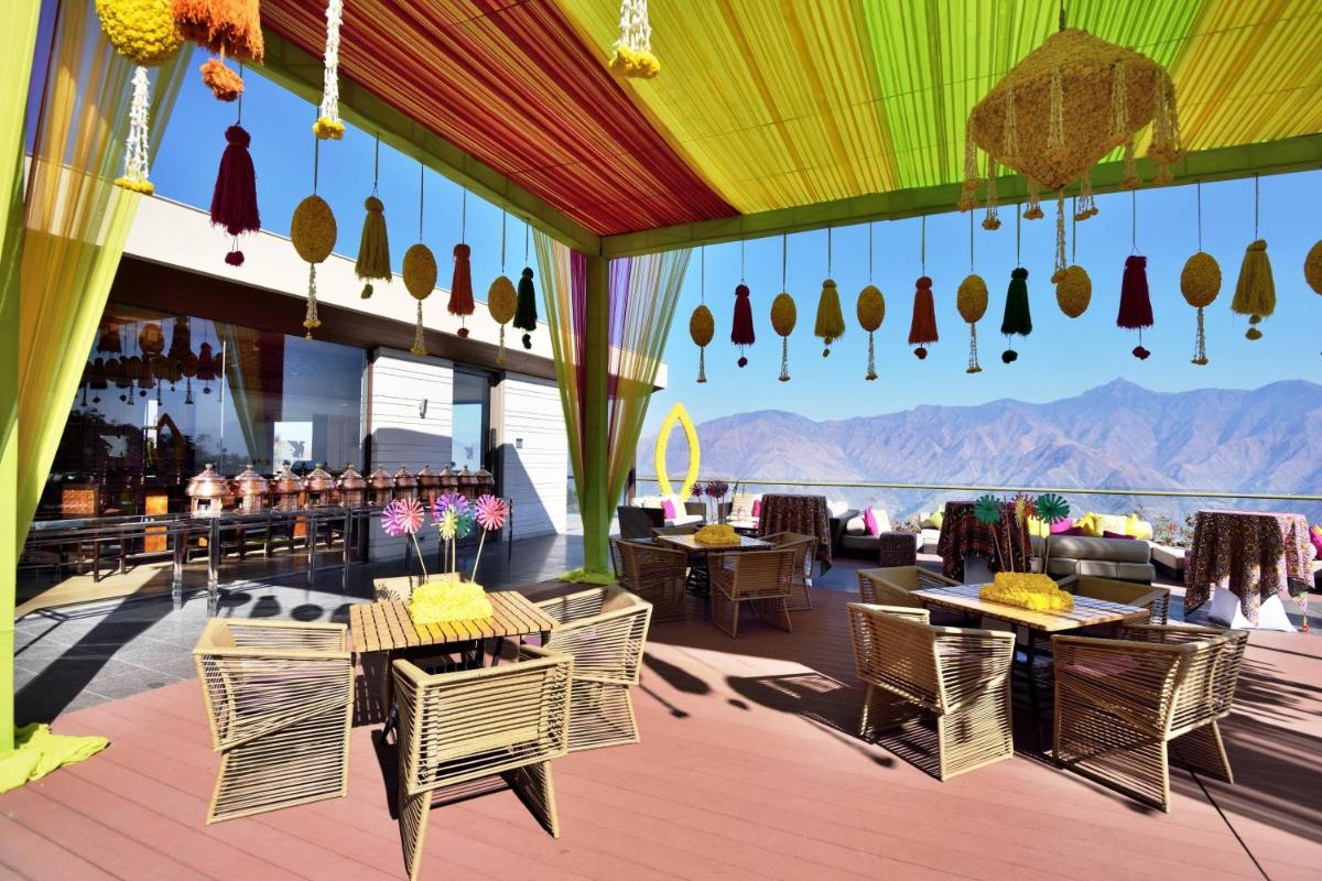 a patio with tables and chairs and a view of the mountains at JW Marriott Mussoorie Walnut Grove Resort & Spa in Mussoorie