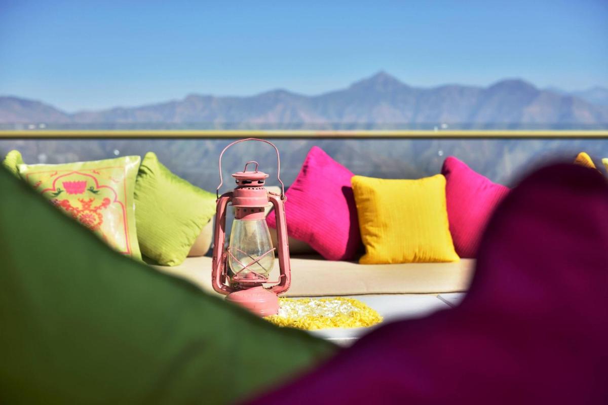 a glass bottle sitting on a couch with colorful pillows at JW Marriott Mussoorie Walnut Grove Resort & Spa in Mussoorie