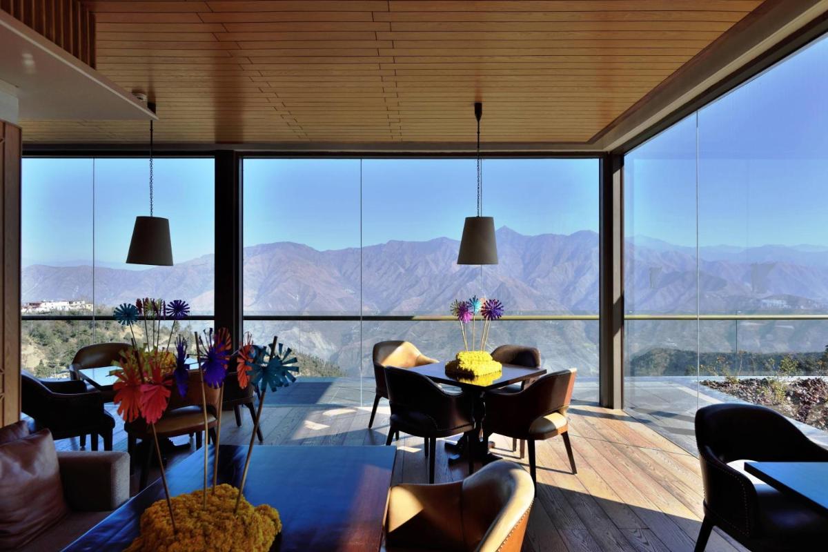 a dining room with a view of the mountains at JW Marriott Mussoorie Walnut Grove Resort & Spa in Mussoorie