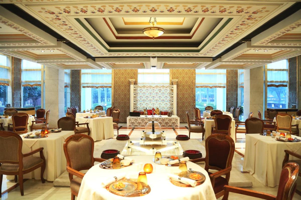 a dining room with tables and chairs in a room at Jaypee Palace Hotel in Agra