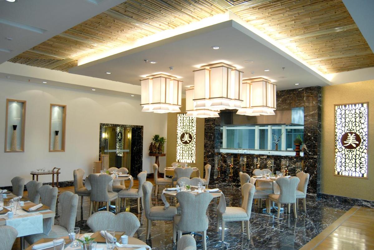 a dining room with tables and chairs and chandeliers at Jaypee Palace Hotel in Agra