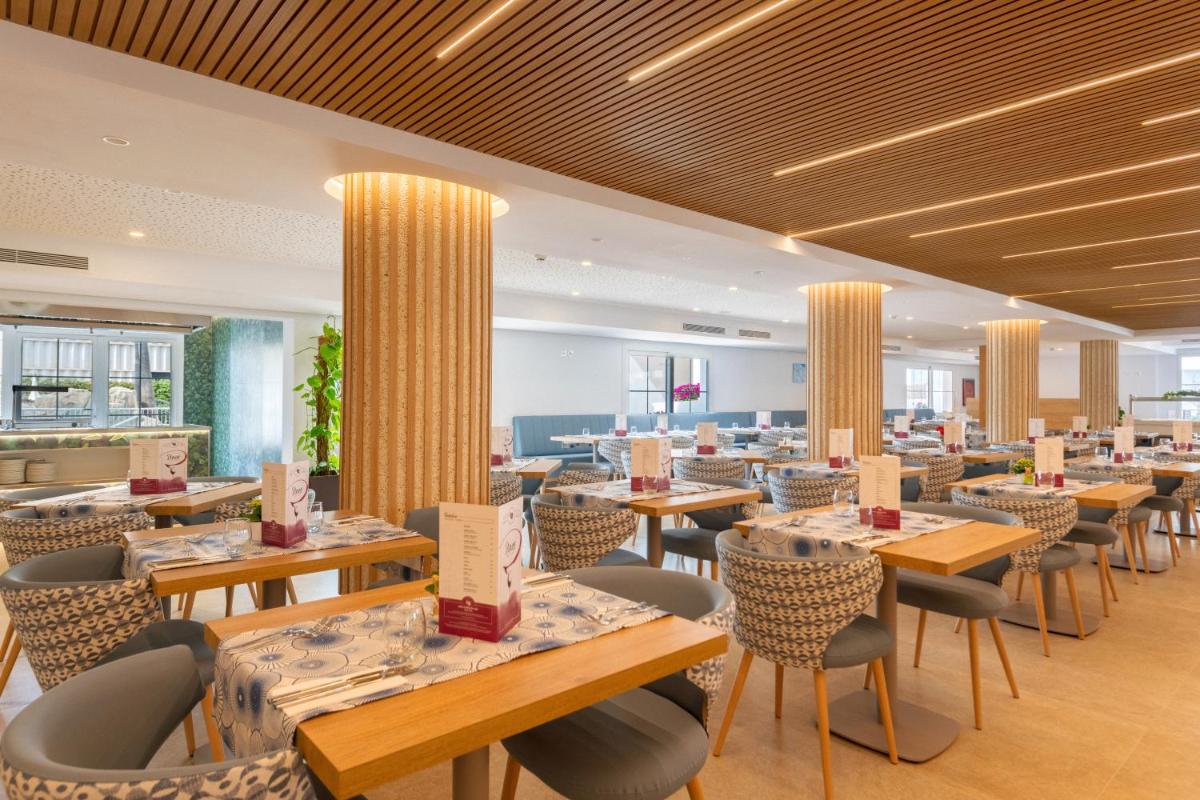 Un restaurante con mesas y sillas en una habitación. en Hotel Capricho, en Cala Ratjada