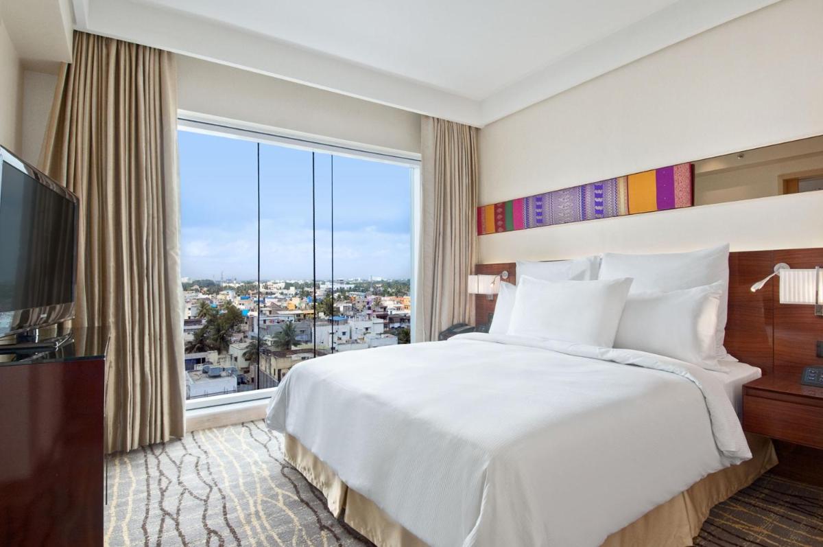 a bedroom with a large bed and a large window at Hilton Chennai in Chennai