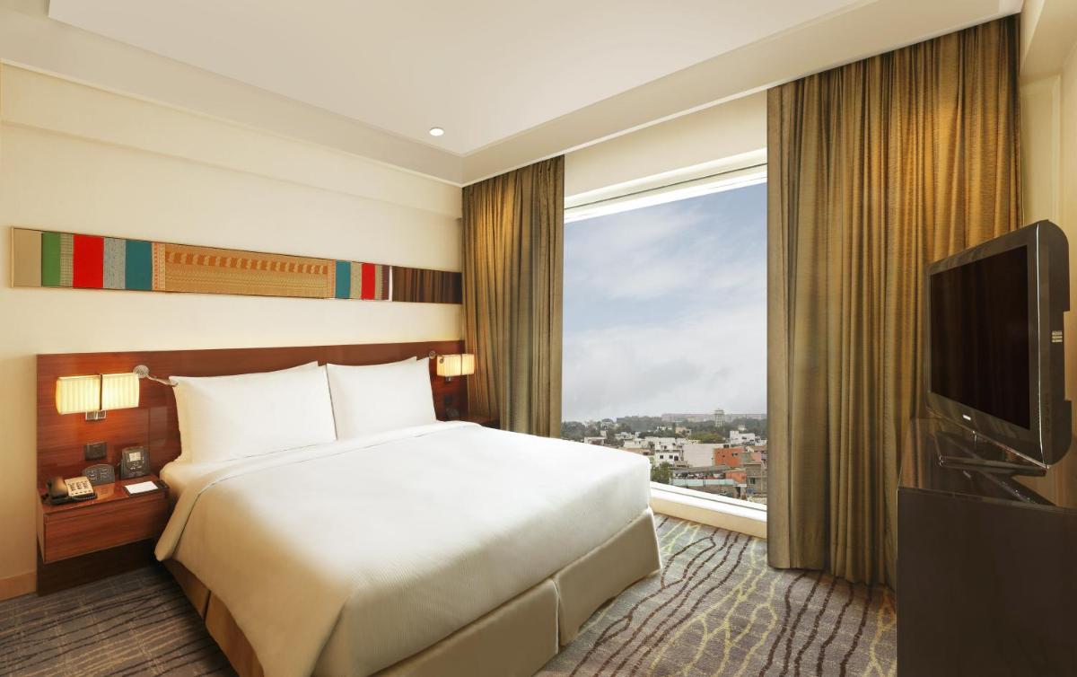 a hotel room with a bed and a large window at Hilton Chennai in Chennai