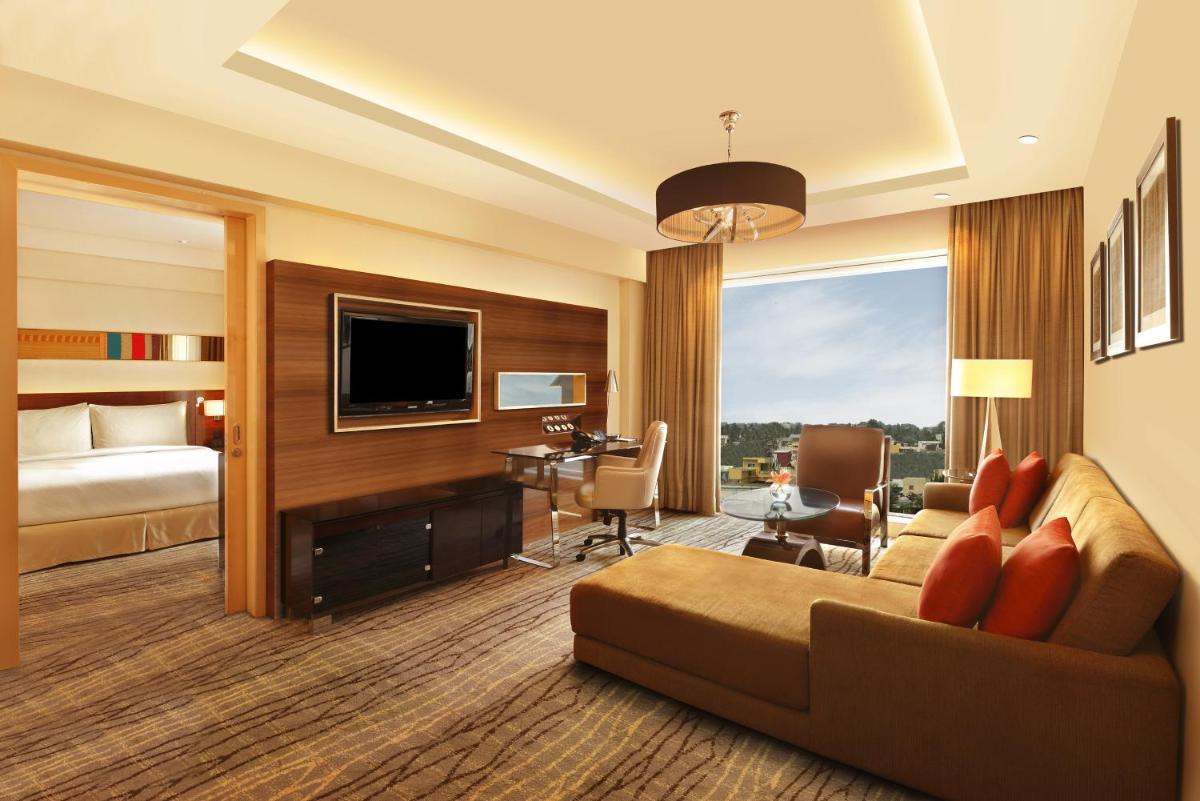 a hotel room with a couch and a bed and a television at Hilton Chennai in Chennai