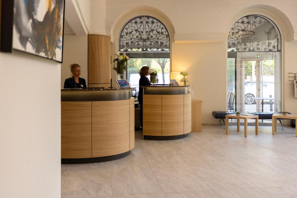 Deux femmes assises à un comptoir dans un hall dans l'établissement Cristal Hôtel & Spa, à Cannes