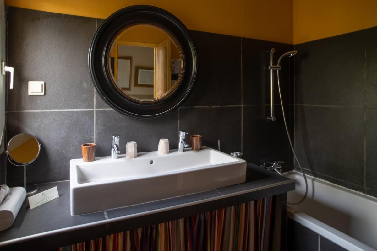 une salle de bains avec lavabo, miroir et baignoire dans l'établissement HOTEL et APPARTEMENTS DOMAINE DES CLOS - Teritoria, à Beaucaire