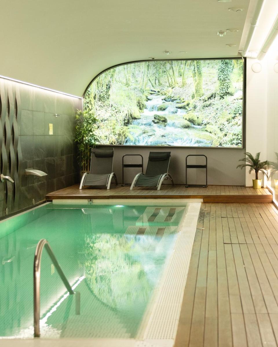 una piscina con 2 sillas y una gran pintura en la pared en Hotel Plaza, en A Coruña